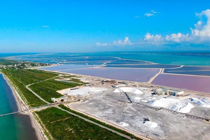 Aerial view of a salt production facility surrounded by pink and blue lagoons.