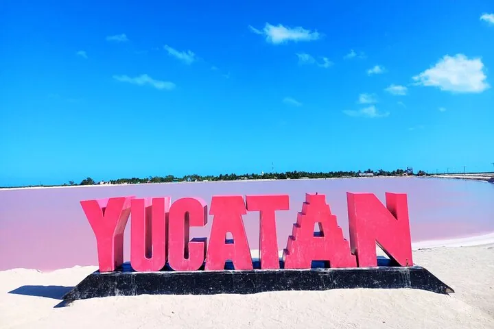 Een groot rood bord met de tekst 'YUCATAN' voor een roze lagune.