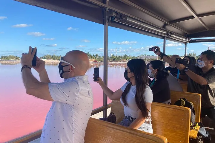 Passagiere in einem Tourfahrzeug fotografieren den rosa See mit ihren Handys.
